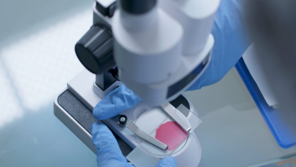 Lab scientist reviewing a blood smear under a microscope