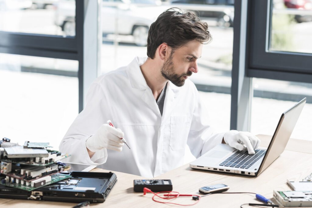 Service engineer running diagnostics on a laptop at a workbench