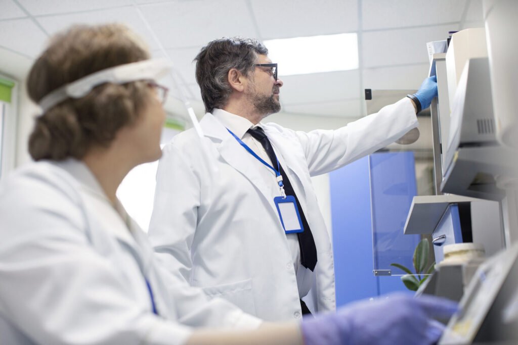 Specialist guiding a laboratory colleague at an analyzer
